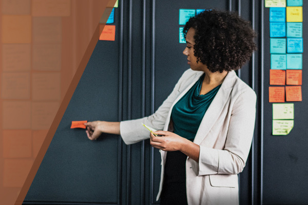 A female teacher placing an orange sticky note on the wall.