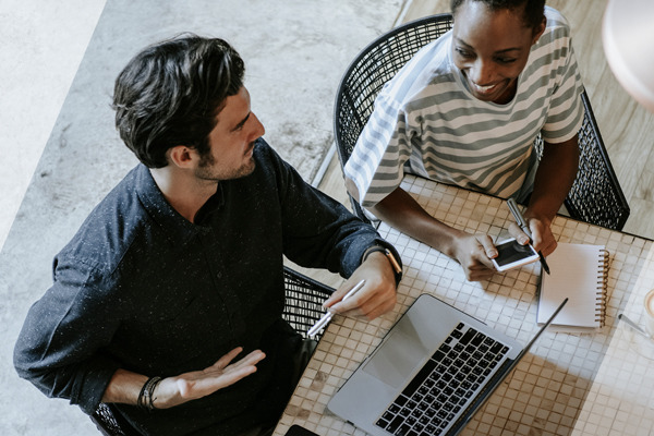 Two people sitting at a desk with a laptop