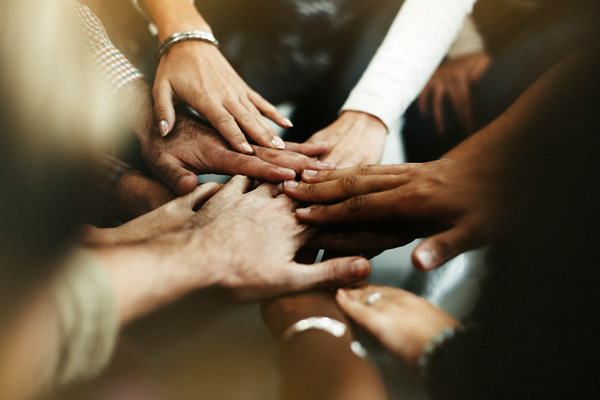 Numerous people putting their hands together in a circle.