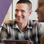 Man smiling while holding tablet.